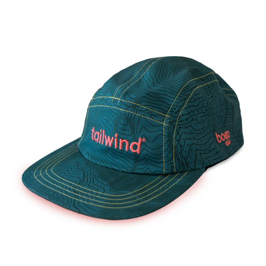 Product photograph of a BOCO Gear technical five-panel running hat for Tailwind Nutrition featuring a dark teal topographic map pattern with pink embroidered logos and yellow contrast stitching on a white background