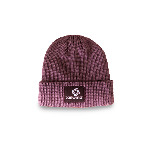 Product photograph by Tailwind Nutrition of a mauve waffle-knit beanie centered on a white background featuring a thick textured weave and a black square patch with a white spiral logo and brand name