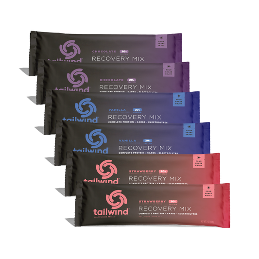 Digital product photography of Tailwind Nutrition Recovery Mix stick packs stacked diagonally against a black backdrop featuring vibrant purple, blue, and pink gradient packaging with the brand's distinctive swirl logo and 20g protein labels