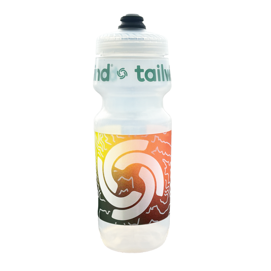 Product photograph by Tailwind Nutrition of a clear plastic water bottle on a white background featuring green branding and a vibrant yellow-to-red topographic wrap with a white spiral logo