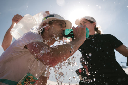 Athletes hydrating mid-run, showcasing the benefits of high carb fueling in hot conditions